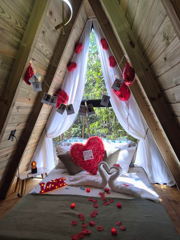 Cama decorada com coração de rosas, cisnes de toalha, balões e fotos penduradas na janela